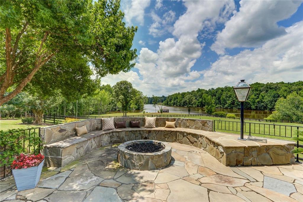 6310 Hunt Road Pleasant Garden, NC 27313 - Photo 3 of 30 Entertaining continues at the flagstone firepit complete with a striking water backdrop! Gas Lanterns, built in seating and a full Viking outdoor kitchen all artfully designed overlooking mature magical landscaping.