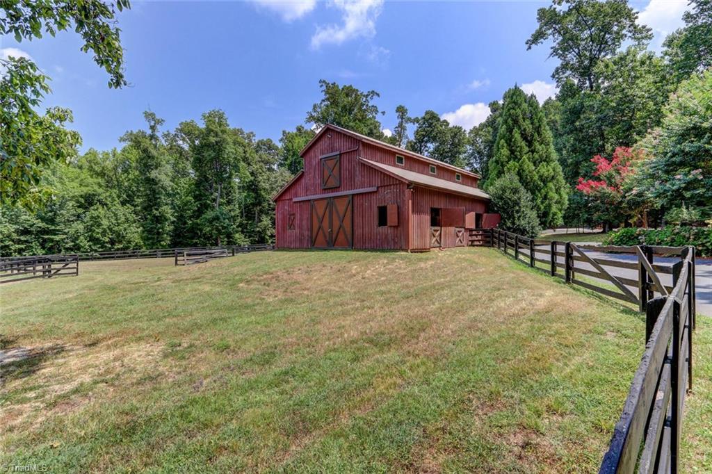 6310 Hunt Road Pleasant Garden, NC 27313 - Photo 25 of 30 Great Barn! Heated Tack/Feed rooms with black walnut walls and wash up sink. Half bath, ceiling fans and concrete aisle. 5 stalls, floored hay storage above, adjoining tractor/trailer garage. 150x75 arena, field hydrants and run in sheds. Turn Key!