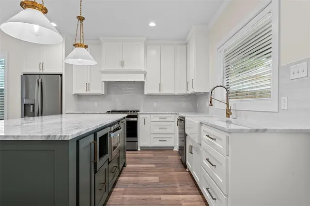 a kitchen with granite countertop a sink stove refrigerator and cabinets