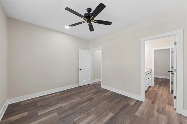an empty room with wooden floor and a ceiling fan