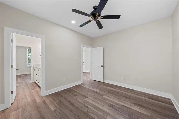 an empty room with wooden floor and a ceiling fan