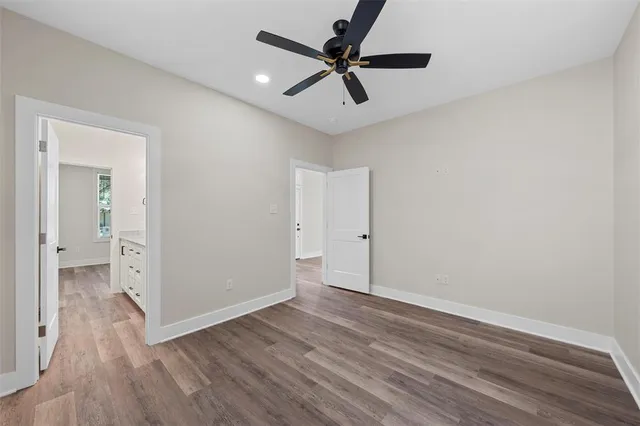 an empty room with wooden floor and a ceiling fan