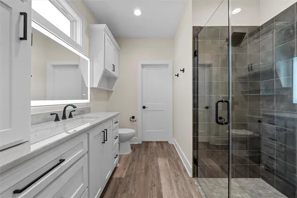 a bathroom with a granite countertop sink a toilet and shower