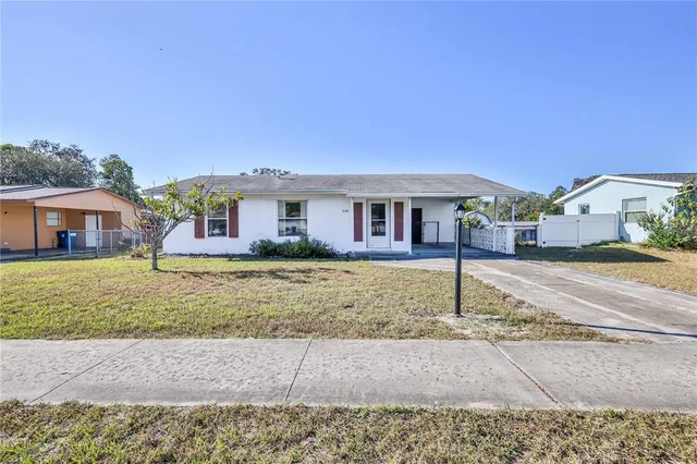 a view of house with a big yard and large trees