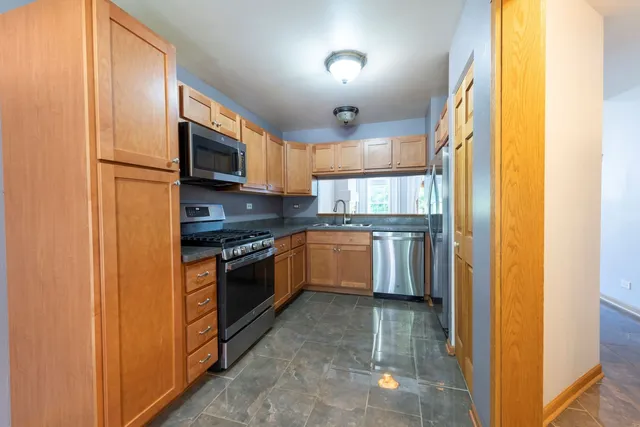 a kitchen with stainless steel appliances granite countertop a stove a sink and a refrigerator
