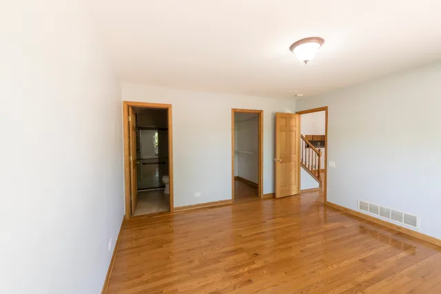 a view of an empty room with wooden floor and closet
