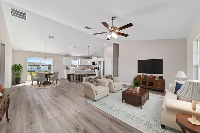a view of a dining room and livingroom with furniture wooden floor kitchen view