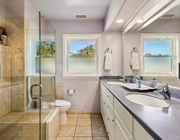 a bathroom with a granite countertop sink a toilet a mirror and shower