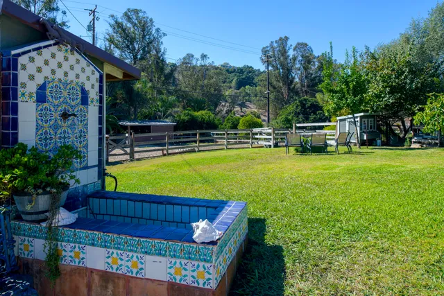 a view of a swimming pool with a bench and trees in the background