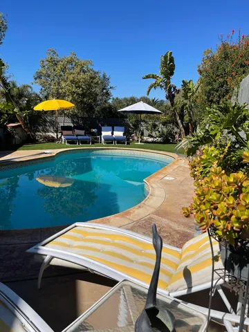 a view of a swimming pool with lawn chairs under an umbrella