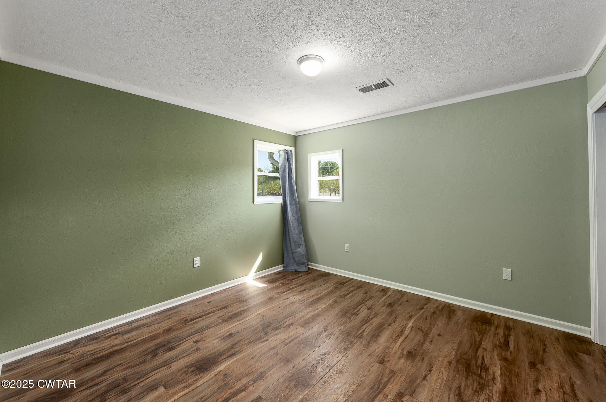 668 Bowman Road Medon, TN 38356 - Photo 19 of 24 an empty room with wooden floor and windows