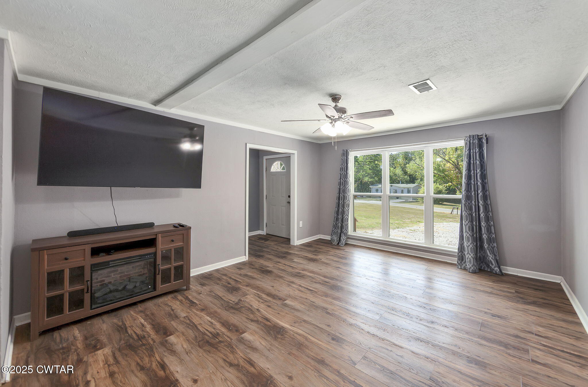 668 Bowman Road Medon, TN 38356 - Photo 7 of 24 a view of a livingroom with a flat screen tv wooden floor and a ceiling fan