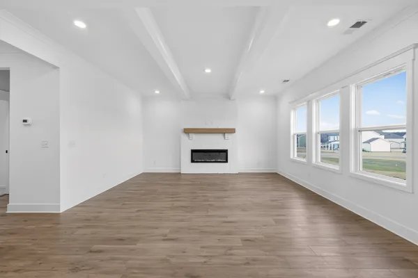 an empty room with windows and fireplace