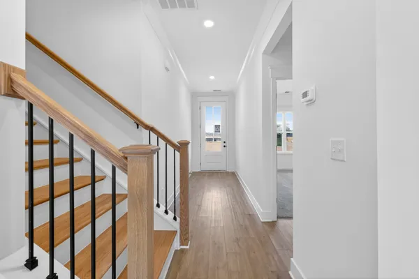 a view of a hallway with wooden floor and staircase