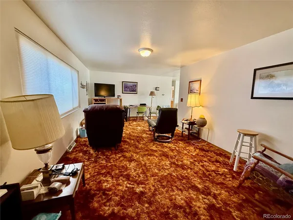 a living room with furniture a flat screen tv and kitchen view
