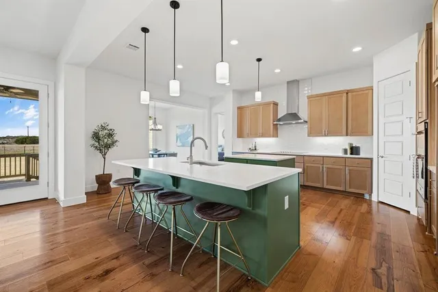 a large kitchen with kitchen island a dining table chairs and a wooden floor