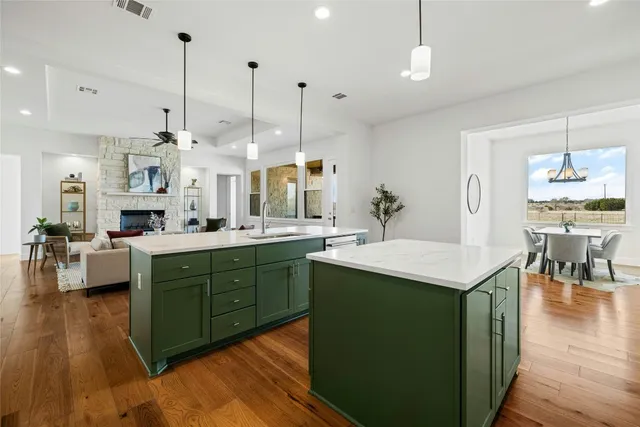 a kitchen with kitchen island granite countertop a sink a counter space and living room view