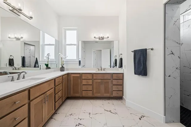 a spacious bathroom with a double vanity sink a mirror and shower