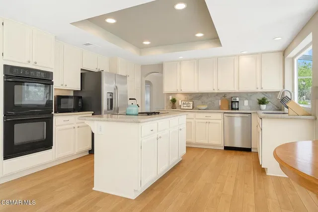 a kitchen with stainless steel appliances granite countertop a refrigerator a sink a stove and wooden floors