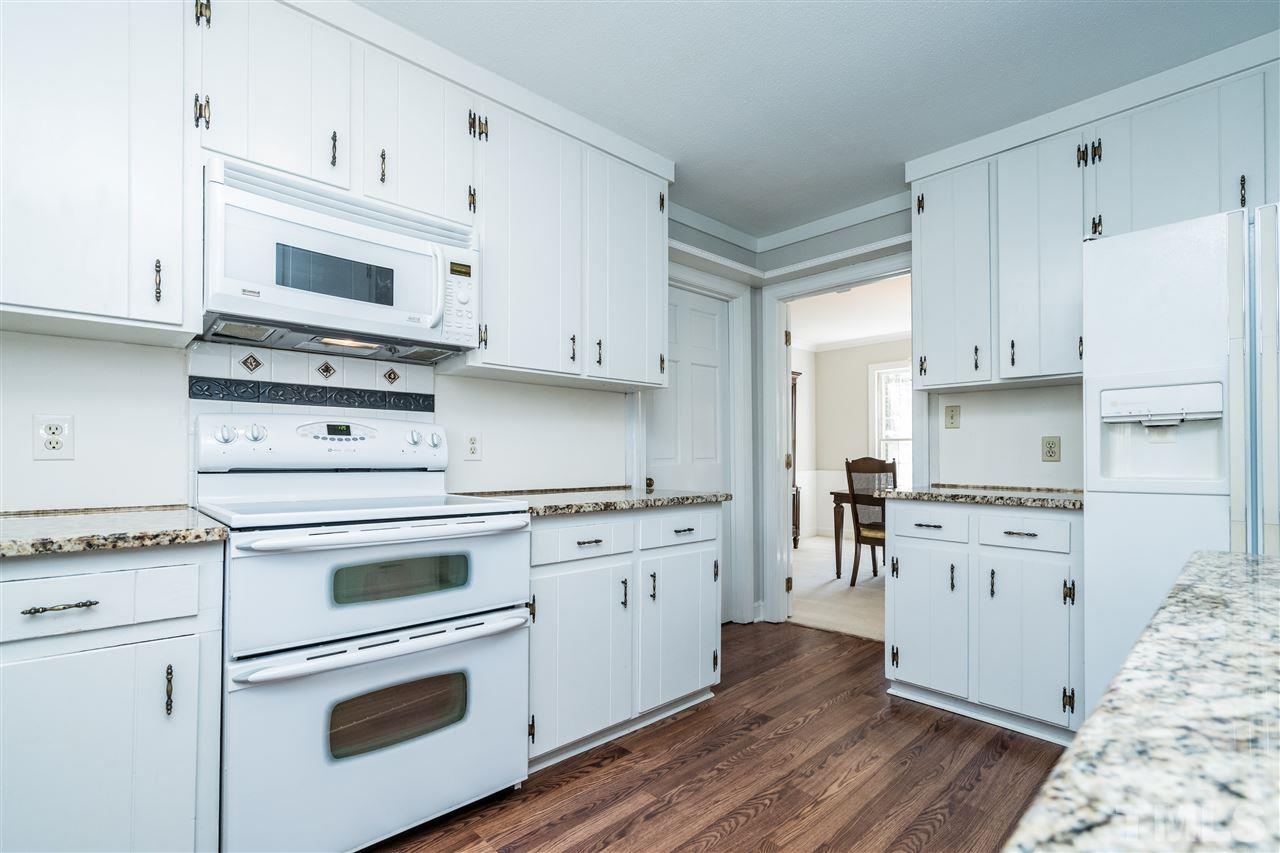 4516 Connell Drive Raleigh, NC 27612 - Photo 13 of 28 a kitchen with granite countertop white cabinets and white appliances