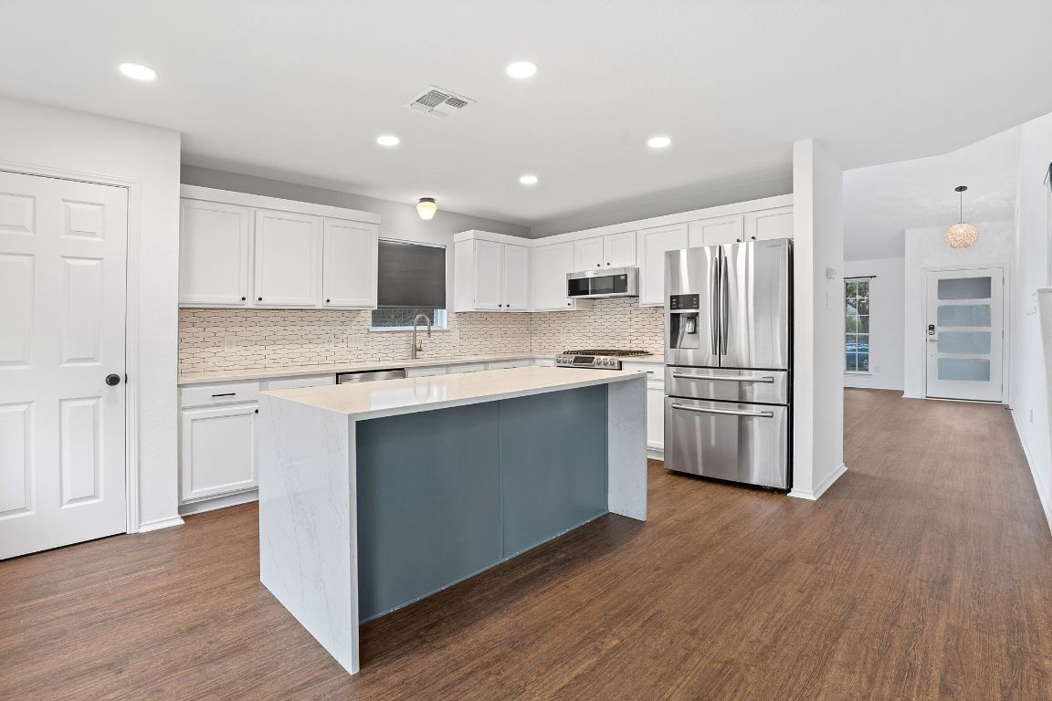 a kitchen with stainless steel appliances a refrigerator and a stove top oven