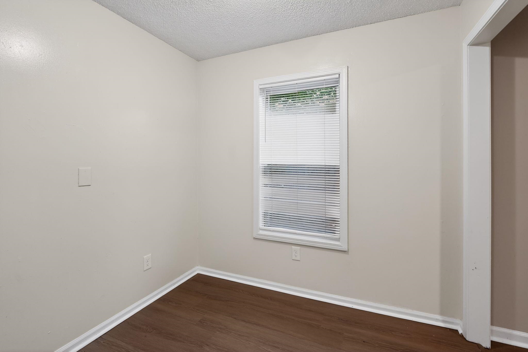 4725 Lofts Road Memphis, TN 38118 - Photo 9 of 32 a view of an empty room with wooden floor and a window