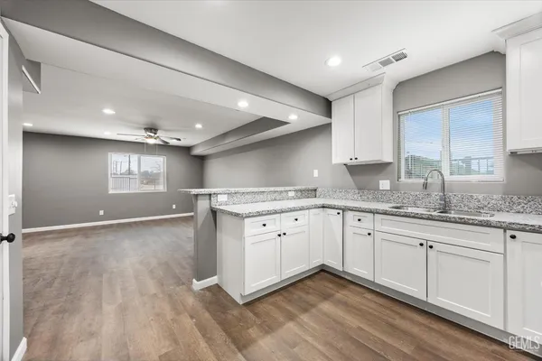 a large kitchen with granite countertop a sink window and cabinets