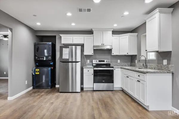a kitchen with stainless steel appliances granite countertop a refrigerator and a stove top oven