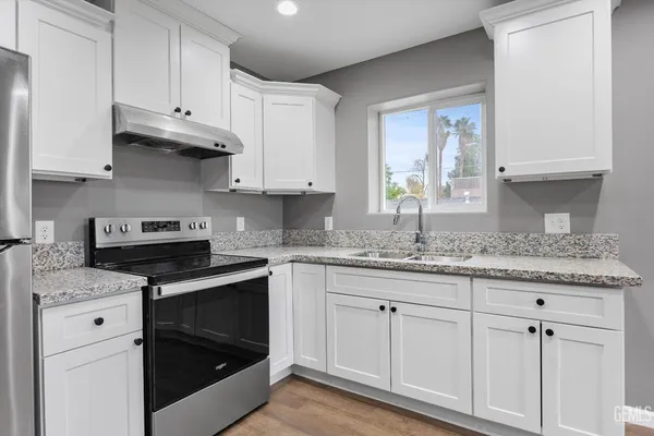 a kitchen with granite countertop white cabinets and a stove