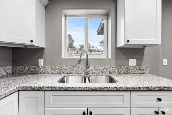 a kitchen with granite countertop a sink and a white cabinets