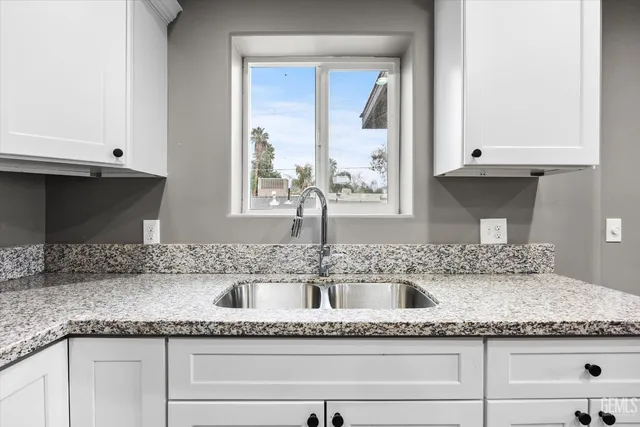 a kitchen with granite countertop a sink and a white cabinets