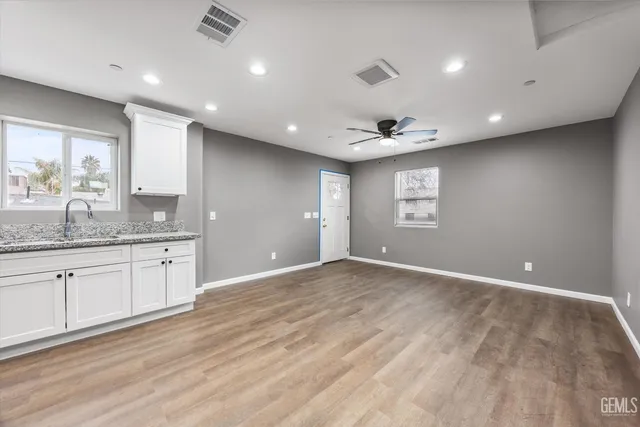 a view of an empty room with window and wooden floor
