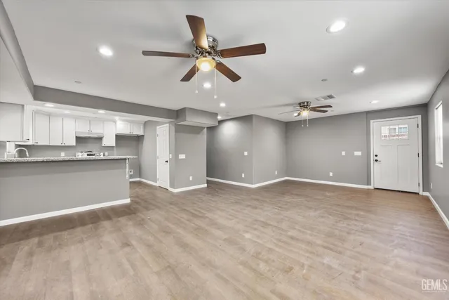 a view of empty room with wooden floor and ceiling fan