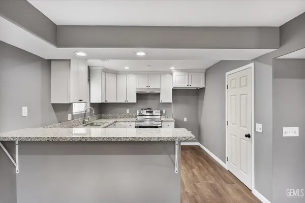 a large white kitchen with granite countertop a sink and a stove top oven