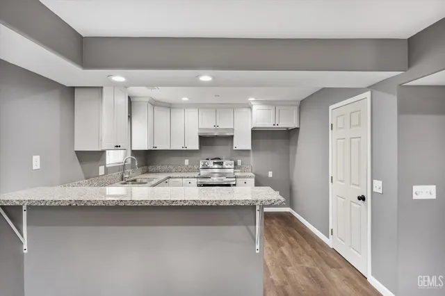 a large white kitchen with granite countertop a sink and a stove top oven