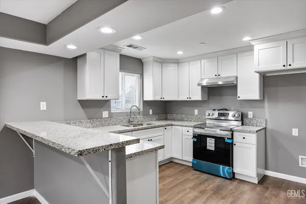 a kitchen with a sink a stove a cabinets and a counter top space