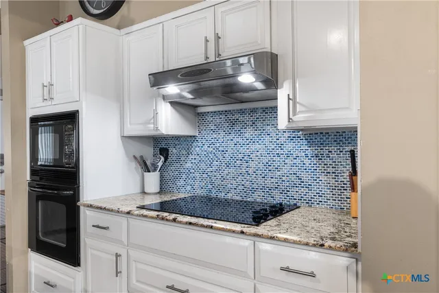 a kitchen with granite countertop white cabinets and stainless steel appliances