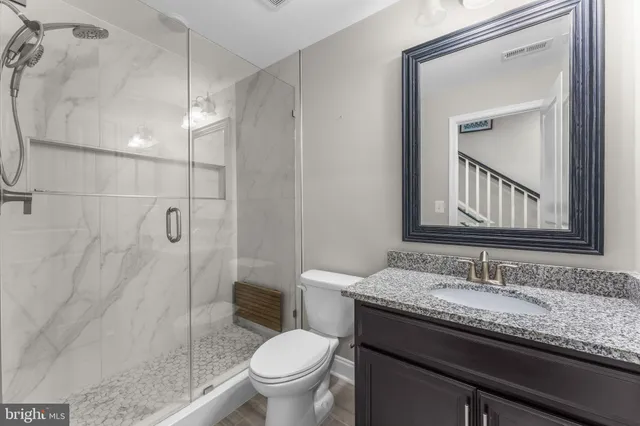 a bathroom with a granite countertop sink a toilet and shower
