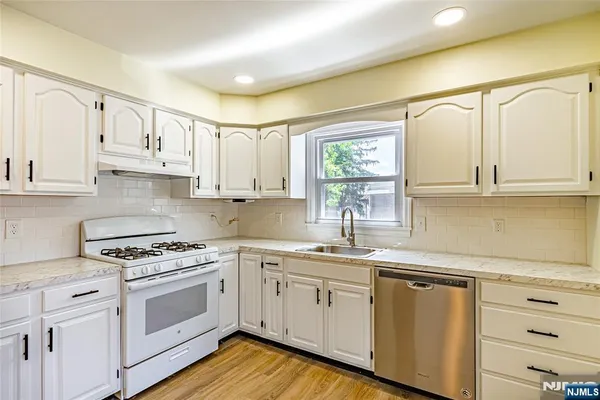 a kitchen with granite countertop white cabinets and white appliances