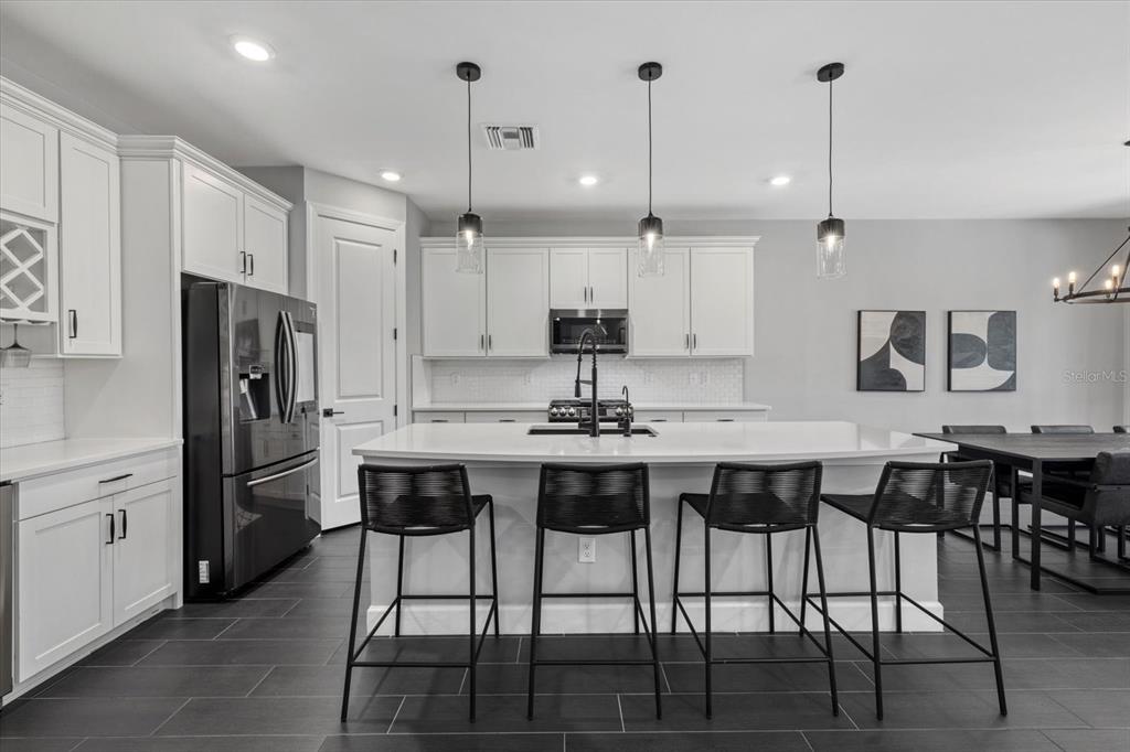 3508 Anchor Bay Trail Lakewood Ranch, FL 34211 - Photo 9 of 74 a kitchen with stainless steel appliances kitchen island granite countertop a dining table chairs and white cabinets