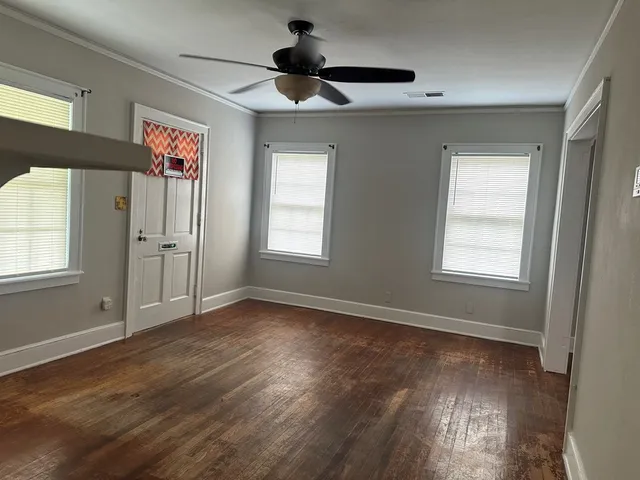 a view of an empty room with wooden floor and a window