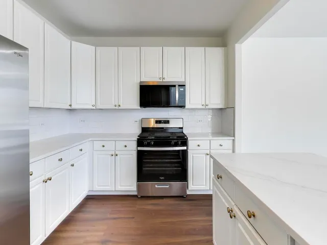 an empty room with wooden floor a fireplace and windows