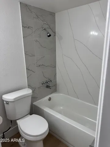 a white toilet sitting next to a bath tub and a shower
