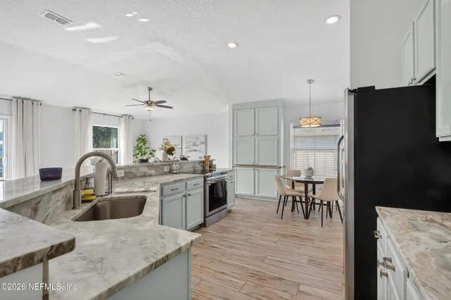 a kitchen with a kitchen island a sink dishwasher a stove and a dining table with wooden floor