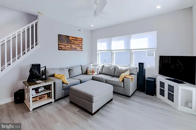 a living room with furniture a flat screen tv and a window
