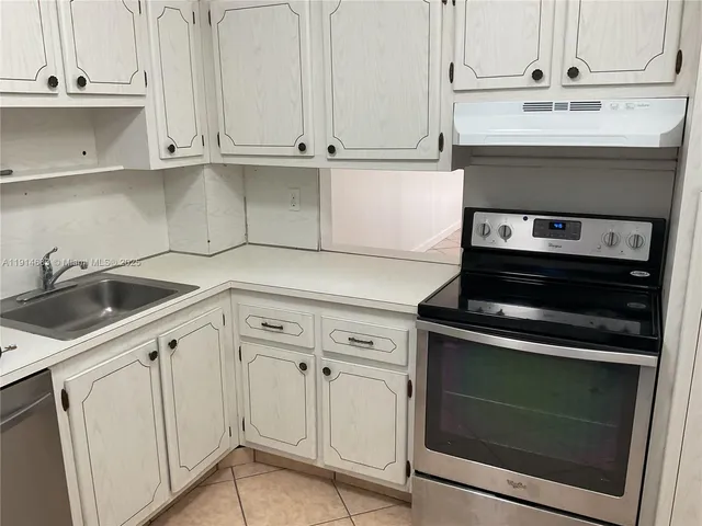 a kitchen with white cabinets and a stove with a sink