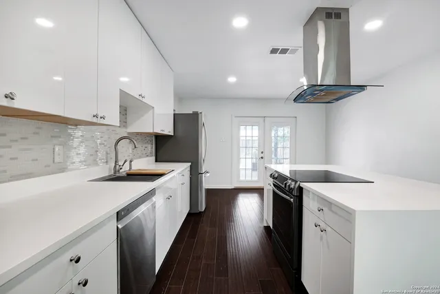 a kitchen with a sink a stove cabinets and wooden floor