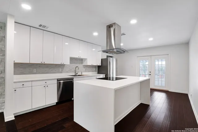 a kitchen with a sink a refrigerator and wooden floor