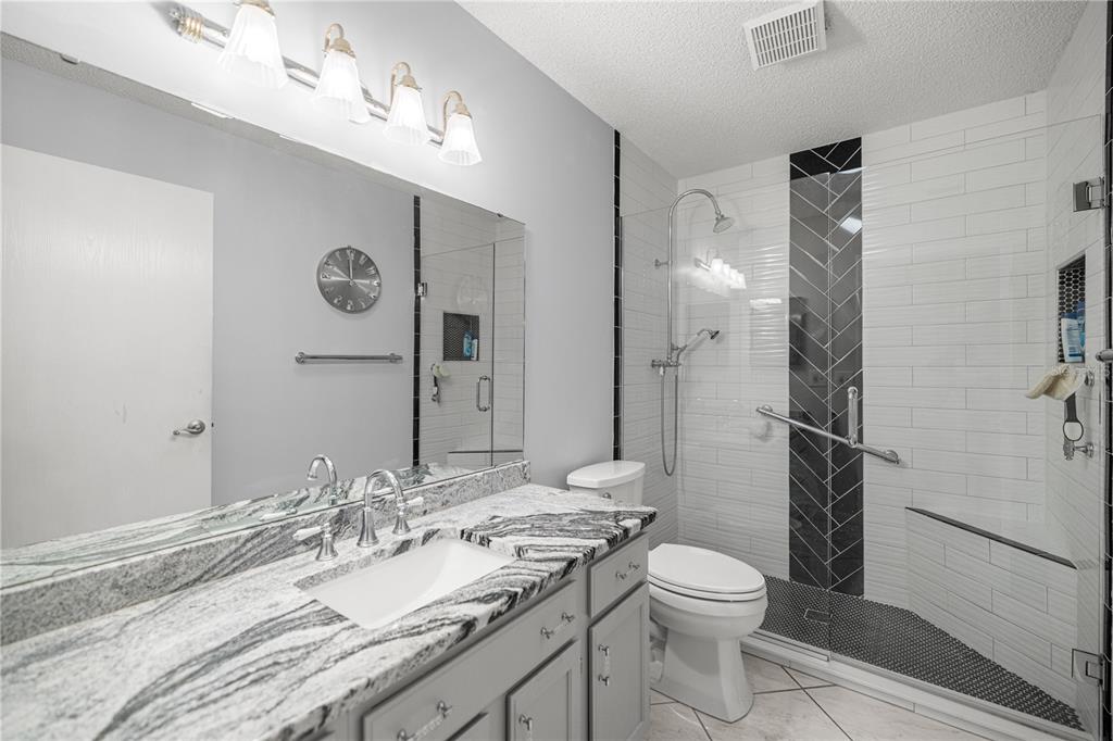 9438 Southwest 85th Avenue, Unit B Ocala, FL 34481 - Photo 16 of 32 a bathroom with a granite countertop sink toilet and shower