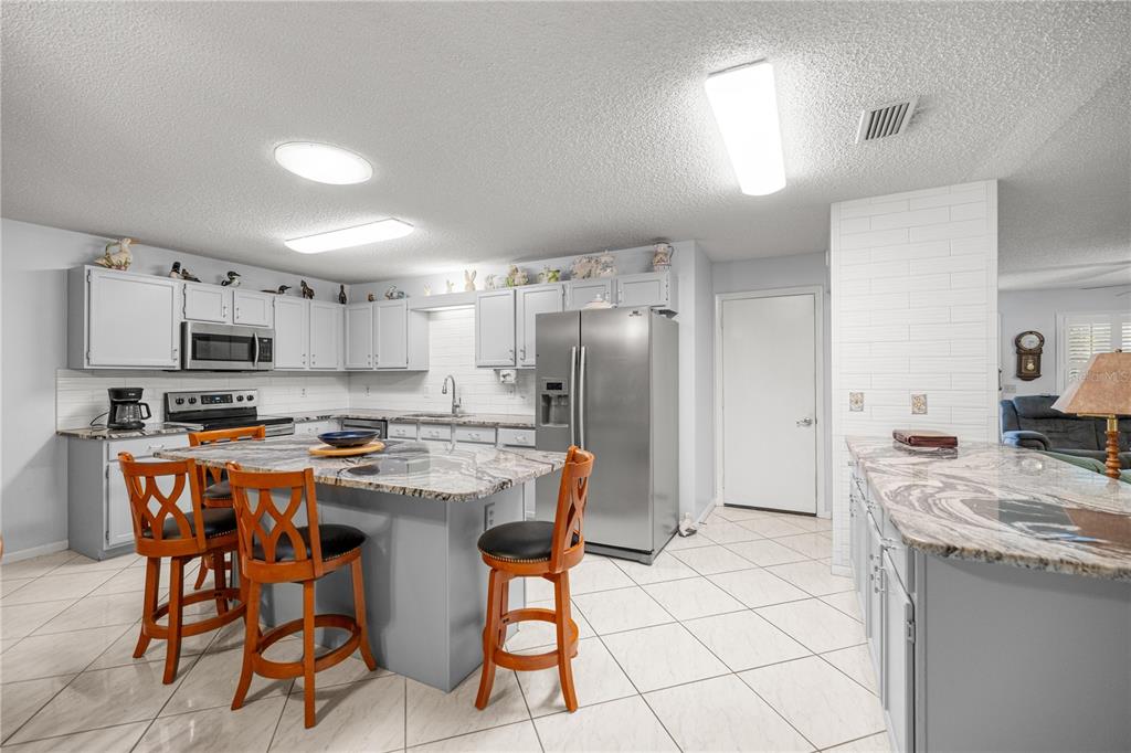 9438 Southwest 85th Avenue, Unit B Ocala, FL 34481 - Photo 5 of 32 a kitchen with stainless steel appliances kitchen island granite countertop a dining table chairs and a refrigerator